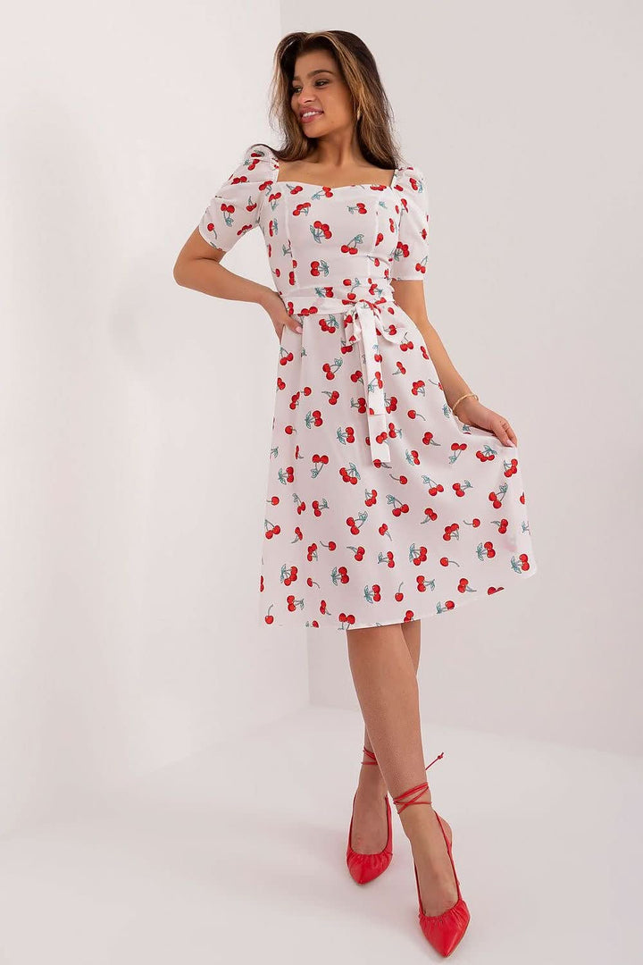 Flared summer youth dress featuring a cherry print, heart-shaped neckline, buff sleeves, tie belt, and discreet back zipper