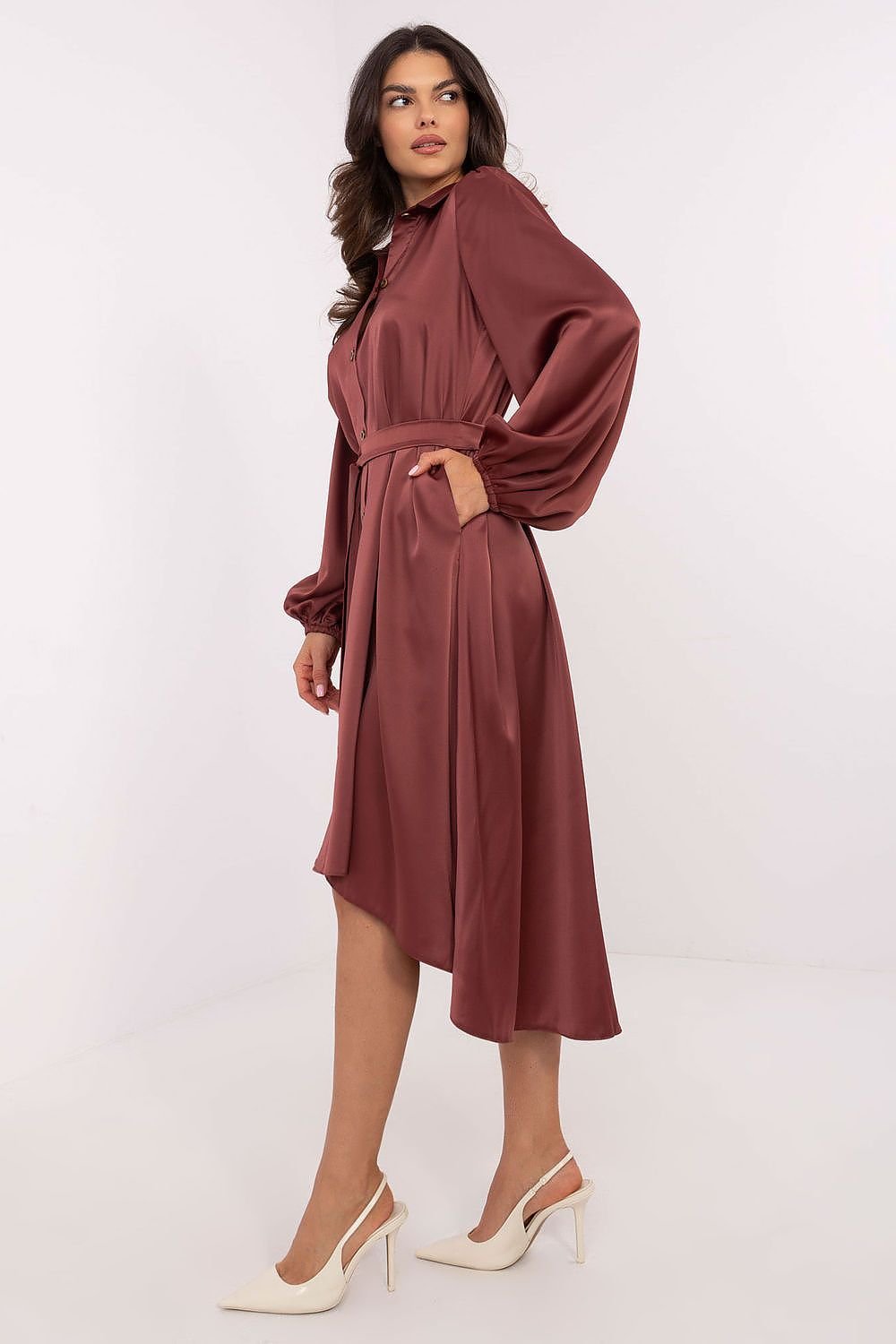 A stylish midi-length shirt dress featuring an asymmetrical cut, smooth pattern, collared neckline, and button closure. Designed with puff cuffed sleeves, a tie belt to define the waist, and practical slip pockets. Made from a soft viscose-polyester blend for comfort and elegance, perfect for work or formal occasions.






