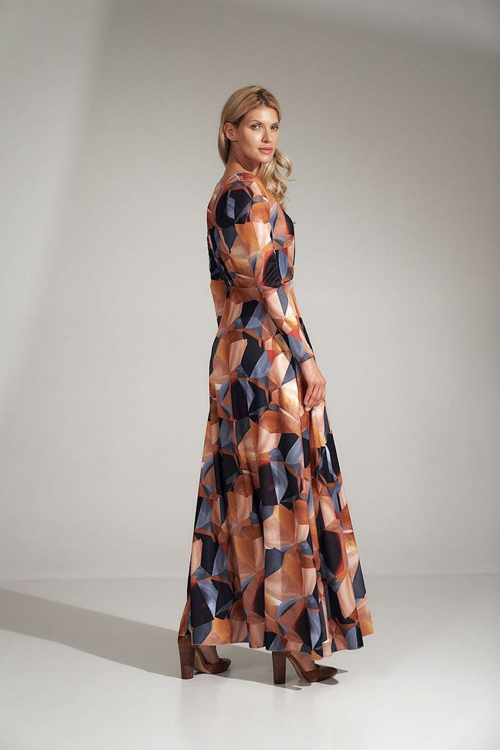This stunning long dress features a flattering heart neckline and a bold geometric pattern, offering a mix of elegance and modern style. The waist is pleated and accented with a sewn-in elastic band, ensuring a comfortable and flattering fit. Long sleeves add sophistication, while the decorative front slit adds a touch of allure and movement. Made from elastic material, this dress provides flexibility and ease of wear, and it’s designed without any fastenings for added convenience. A perfect combination of 