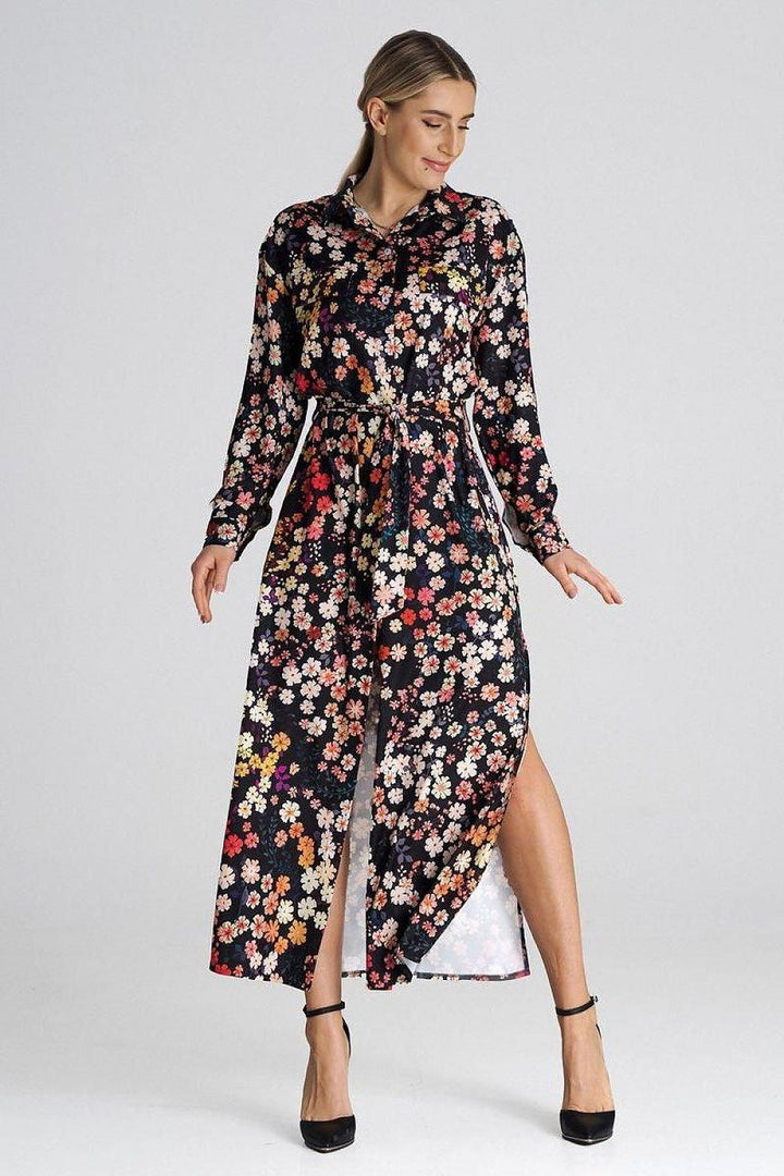 Maxi shirt dress with a collar. Decorative tabs on the bust line. Long sleeve finished with a buttoned cuff. Dress buttoned up, tied at the waist. Side slits. Dress without pockets and lining.