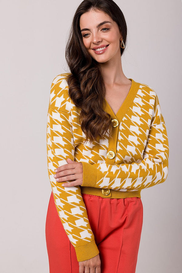Stylish short unbuttoned pepit sweater made from soft acrylic yarn, featuring decorative buttons, smooth pleating, and a lowered shoulder line for a fashionable look. With long sleeves, ribbed hem, and perfect for colder days, this versatile sweater is ideal for both casual and elegant outfits. Made in Poland.