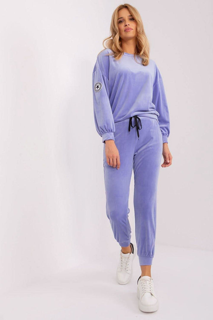 An elegant velour sweatshirt set featuring a round-neck, long-sleeve sweatshirt with a unique patch on one sleeve, paired with tapered pants with a drawstring waist and practical side pockets. Perfect for various occasions, offering a combination of comfort and chic style.






