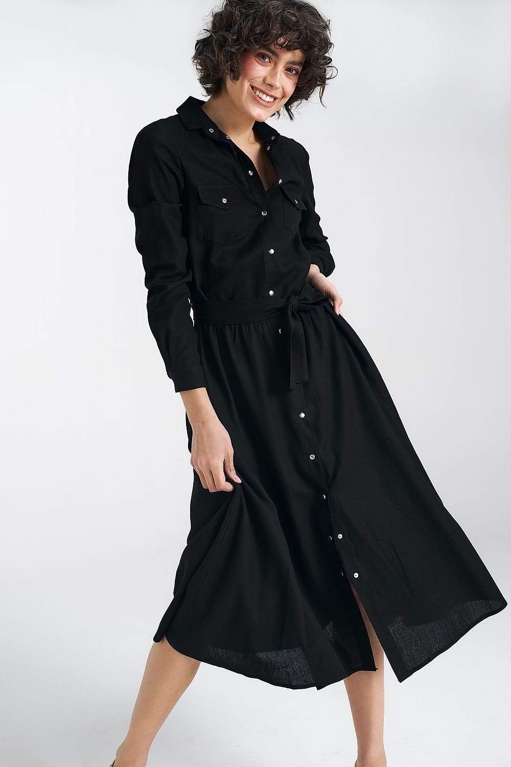 black Regular cut midi dress made of viscose, linen, and cotton, featuring a classic collar, long cuffed sleeves, and decorative pockets. The silver-tone fastening adds a delicate touch, while the belt accentuates the waist. Practical side pockets and an unlined design make this dress ideal for comfort and elegance in both casual and formal settings.






