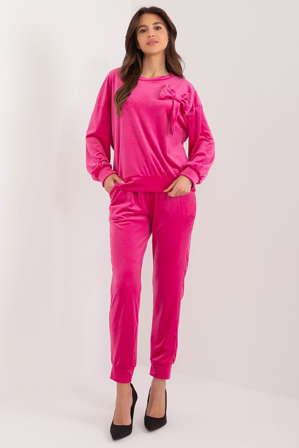 A stylish velour set featuring a sweatshirt with a decorative bow and round neckline, paired with high-waisted pants with a waist tie, side pockets, and leg welts, offering comfort, elegance, and versatility for casual outfits.