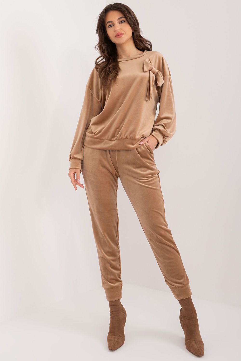 A stylish velour set featuring a sweatshirt with a decorative bow and round neckline, paired with high-waisted pants with a waist tie, side pockets, and leg welts, offering comfort, elegance, and versatility for casual outfits.