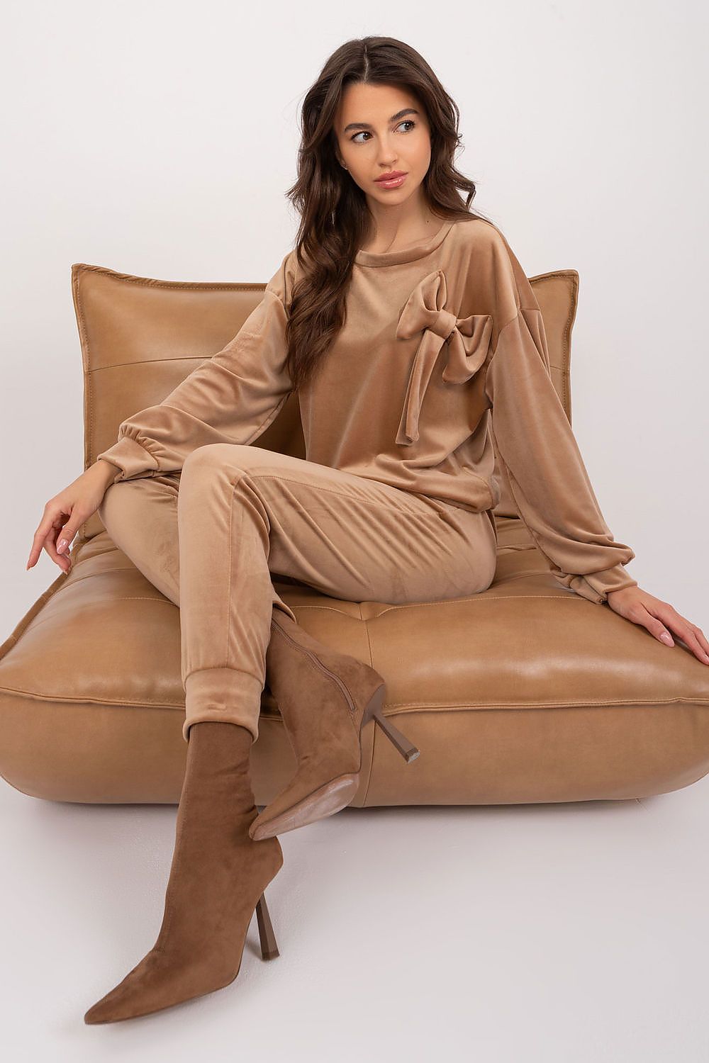 A stylish velour set featuring a sweatshirt with a decorative bow and round neckline, paired with high-waisted pants with a waist tie, side pockets, and leg welts, offering comfort, elegance, and versatility for casual outfits.