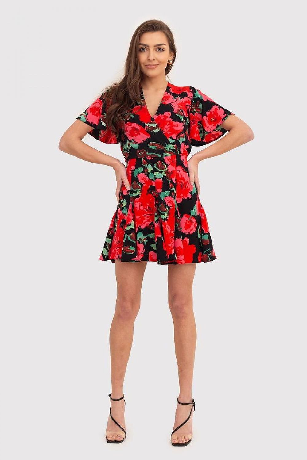 A red draped dress with a floral print, featuring short ruffled sleeves, an envelope-style top, and a skater bottom. The dress fastens with a covered zipper, combining elegance with a playful touch. Perfect for a variety of occasions.






