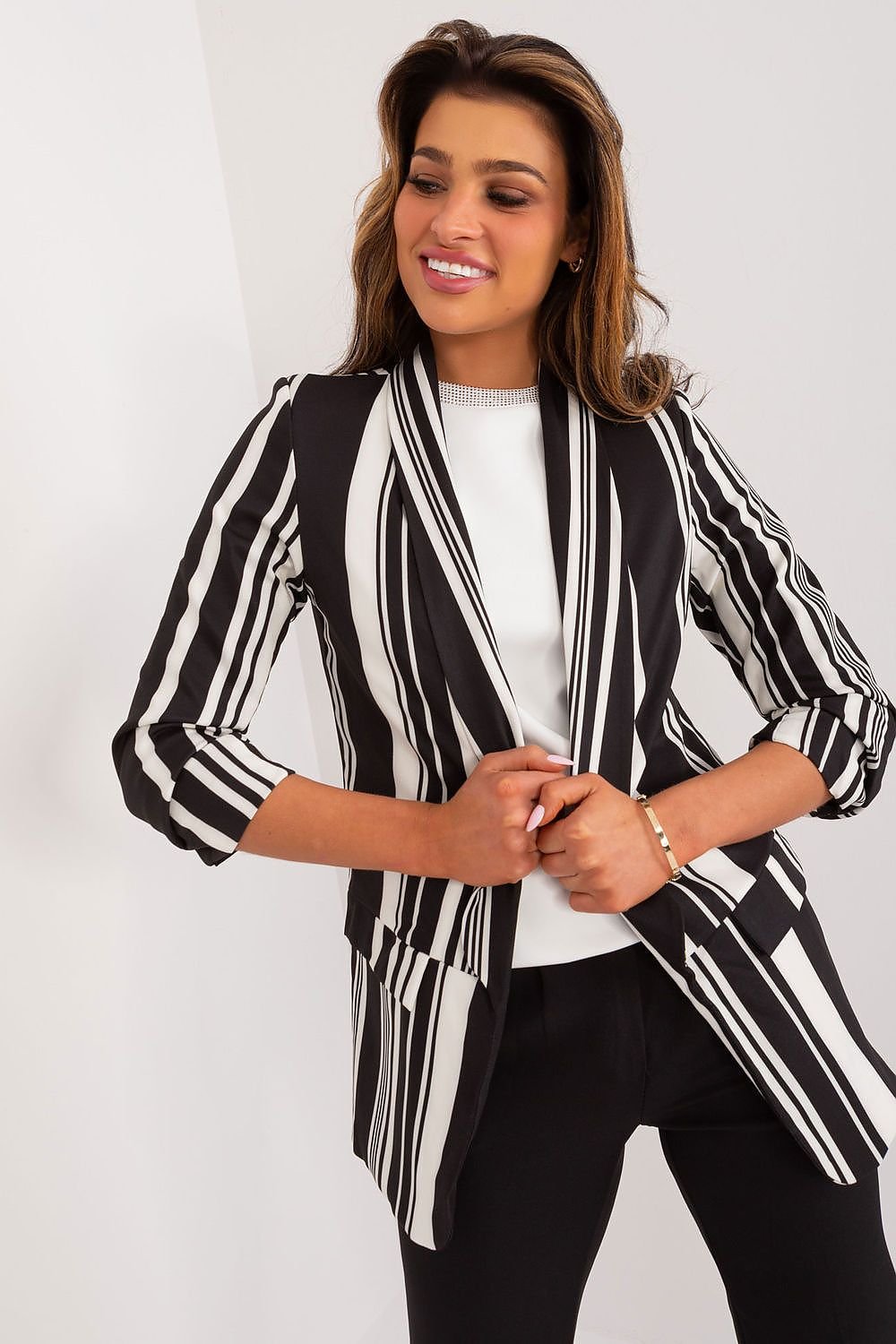 A relaxed striped jacket made of durable polyester, featuring 3/4 sleeves and no fastening for a casual, comfortable style. Lined for a better fit, this jacket is perfect for spring and summer, offering versatility and elegance without sacrificing comfort. Ideal for everyday wear or work, it pairs well with a variety of outfits and suits different silhouettes."