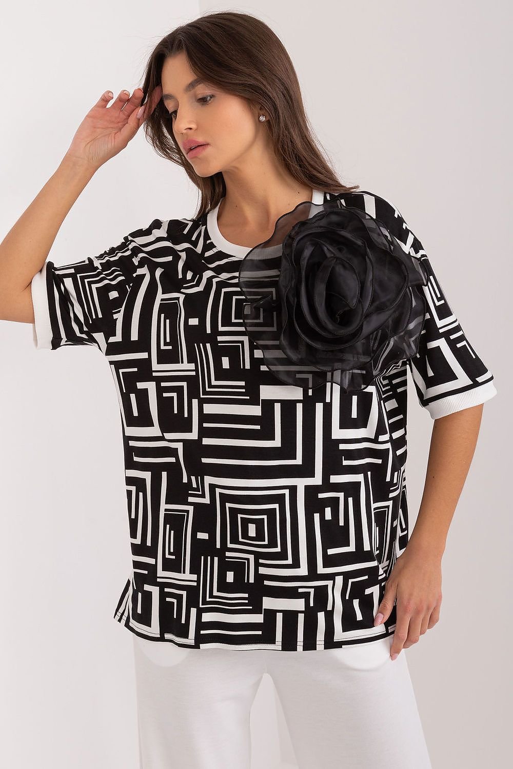 Elegant blouse with a flower-shaped brooch, modern geometric pattern, short sleeves, and round neckline, perfect for work or casual outings.