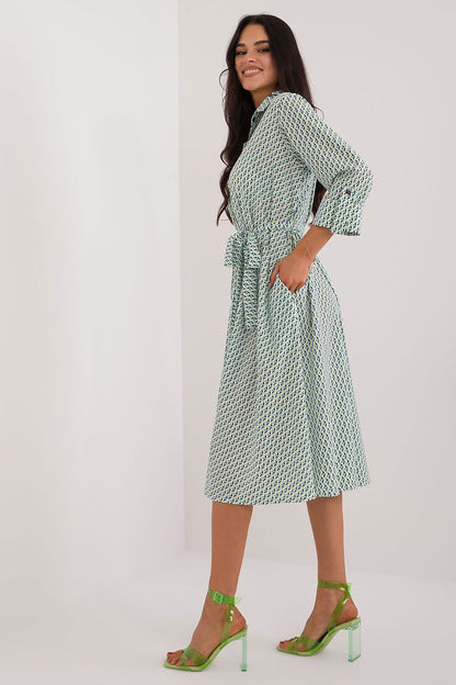 A versatile shirt dress with a flared cut, midi length, and 3/4 sleeves, featuring a muted print, tie belt, buttons, and practical slip pockets, perfect for everyday wear and work.






