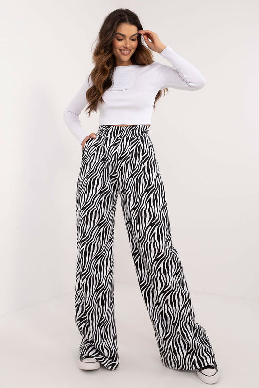 A casual women's set featuring a ribbed long-sleeve blouse with a round neckline and subtle front inscription, paired with high-waisted pants with wide legs and an animal print motif, combining comfort and bold style for everyday wear.