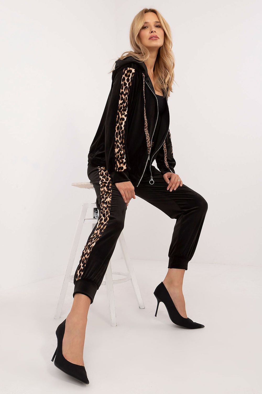 A women's velour set featuring a zippered sweatshirt with long sleeves, a hood, and leopard-patterned stripes on the sleeves. Paired with high-waisted pants tied at the waist, featuring slip-in side pockets and animal-patterned piping on the legs for a stylish, sporty look. Ideal for casual everyday wear.






