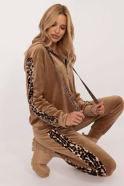 A women's velour set featuring a zippered sweatshirt with long sleeves, a hood, and leopard-patterned stripes on the sleeves. Paired with high-waisted pants tied at the waist, featuring slip-in side pockets and animal-patterned piping on the legs for a stylish, sporty look. Ideal for casual everyday wear.






