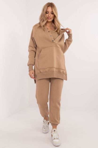 A cozy women's set featuring a mélange-patterned T-shirt, a long-sleeve sweatshirt with a hood and press-stud fastening, and high-waisted pants with ribbed cuffs, offering comfort and style for colder days and everyday outings.