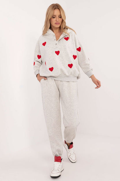 A cozy women's casual set featuring a long-sleeve hooded sweatshirt with a half-zip fastening and adorable heart-shaped patches. Paired with high-waisted jogger pants with ribbed cuffs, a tie waist, and side slip pockets, this set offers warmth, comfort, and flexibility. Made from a cotton-elastane blend, it's perfect for colder days and stylish everyday outings.






