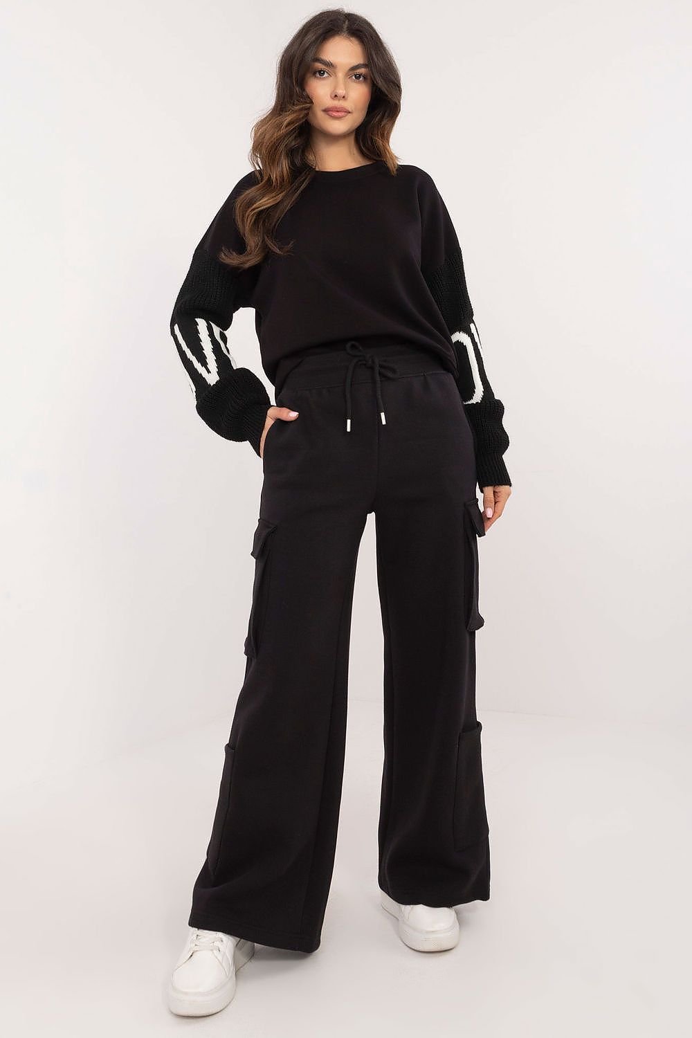 Versatile high-rise cargo tracksuit trousers with a waist tie for an adjustable fit. Made from a cotton-polyester blend, featuring wide legs, side cargo pockets, and additional slip-in pockets. Ideal for combining comfort and style on casual days.






