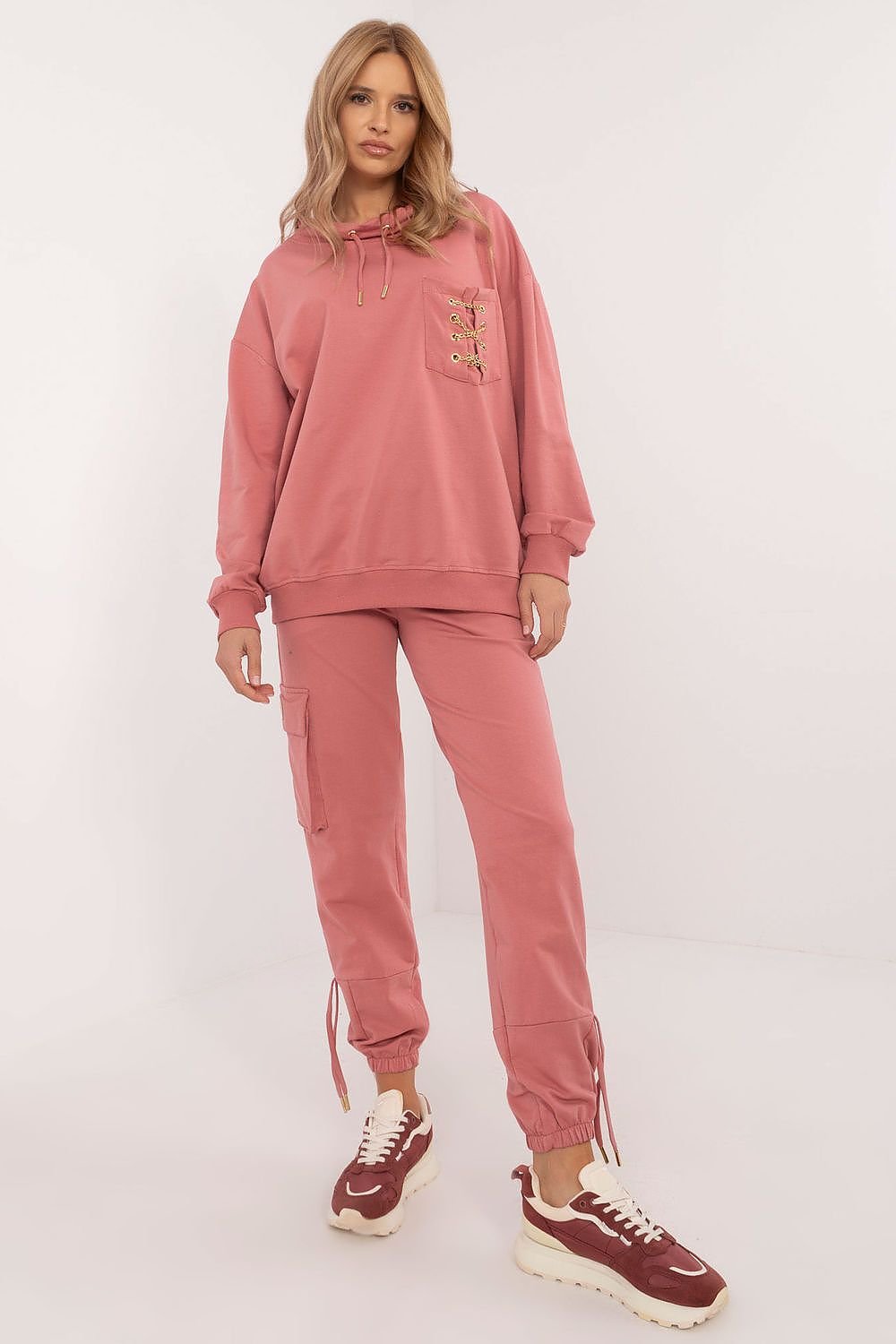 Trendy women's tracksuit set made from high-quality cotton with a touch of elastane for comfort and flexibility. The hoodie features a round neckline, front pocket with a chic chain detail, and the high-waisted pants have slip pockets and cuffs for a perfect fit. The smooth pattern makes it versatile and easy to style for any occasion. Ideal for women seeking comfort and style.