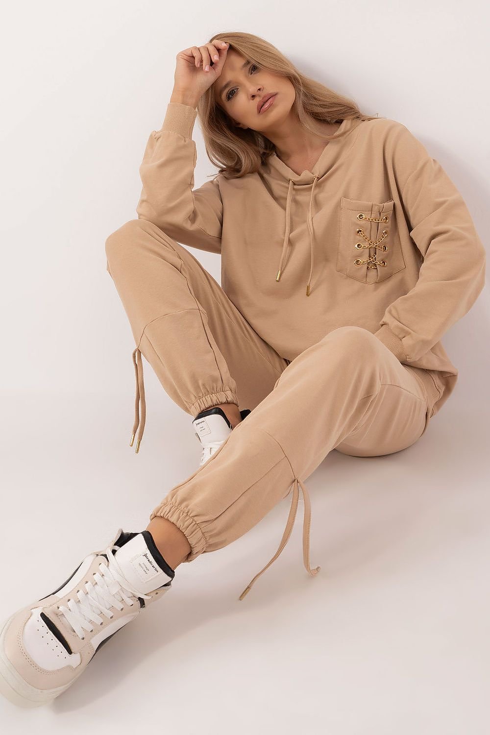 Trendy women's tracksuit set made from high-quality cotton with a touch of elastane for comfort and flexibility. The hoodie features a round neckline, front pocket with a chic chain detail, and the high-waisted pants have slip pockets and cuffs for a perfect fit. The smooth pattern makes it versatile and easy to style for any occasion. Ideal for women seeking comfort and style.