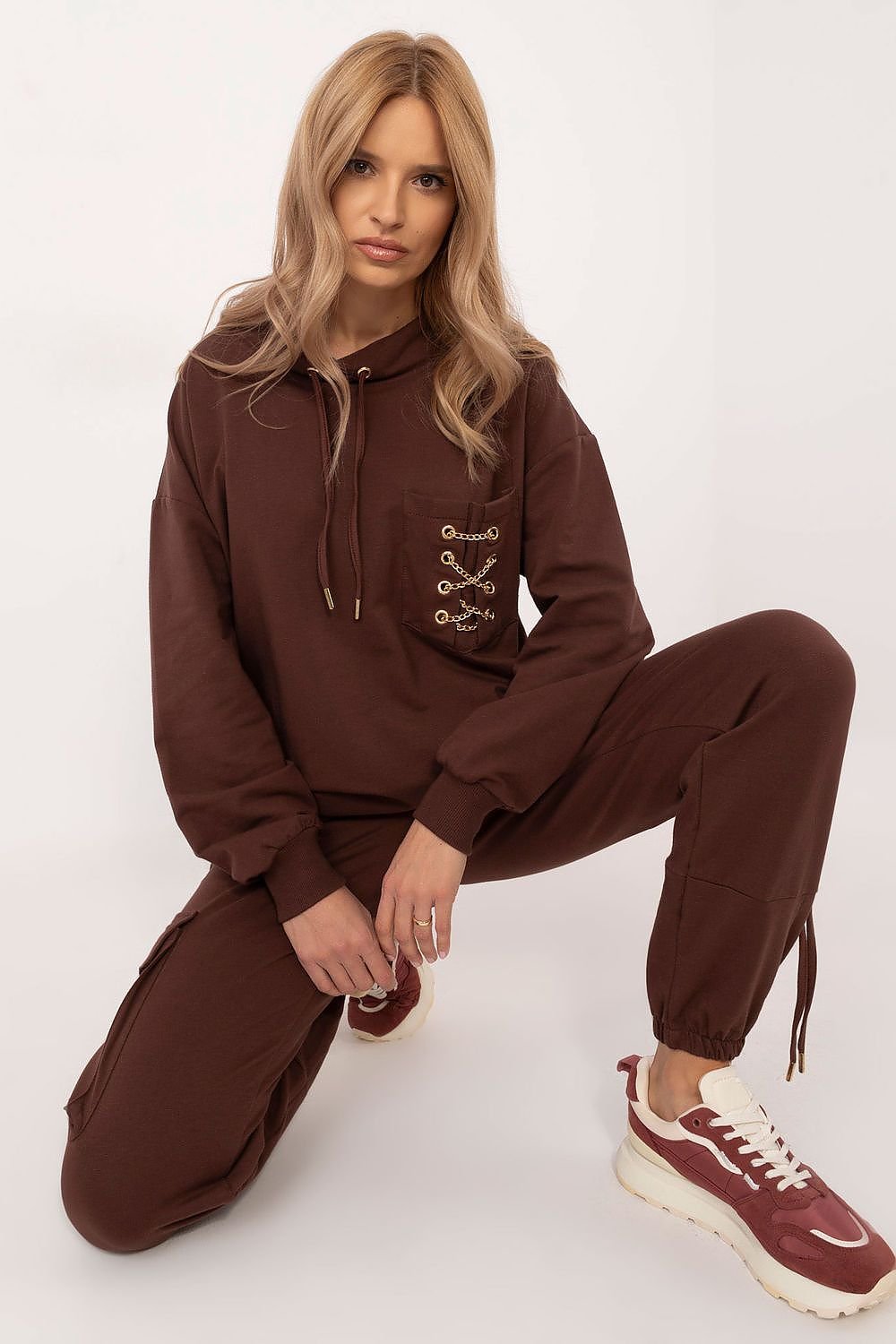 Trendy women's tracksuit set made from high-quality cotton with a touch of elastane for comfort and flexibility. The hoodie features a round neckline, front pocket with a chic chain detail, and the high-waisted pants have slip pockets and cuffs for a perfect fit. The smooth pattern makes it versatile and easy to style for any occasion. Ideal for women seeking comfort and style.