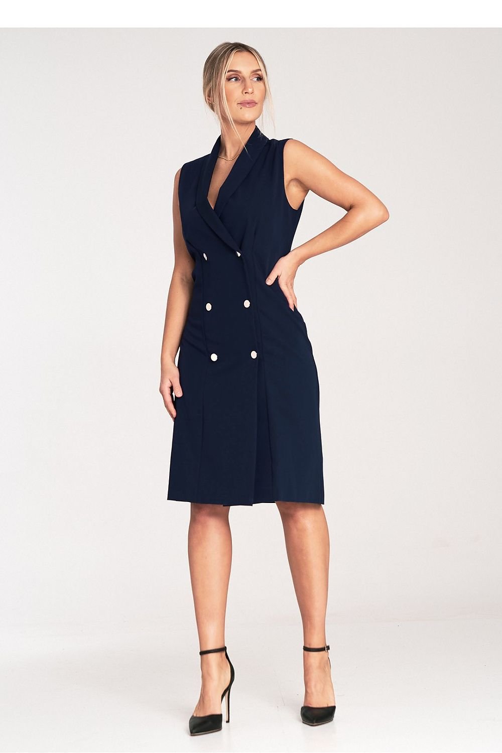 An elegant sleeveless midi dress with narrow lapels, an envelope neckline, a double-breasted closure featuring large decorative snaps, and a slightly flared hem.






