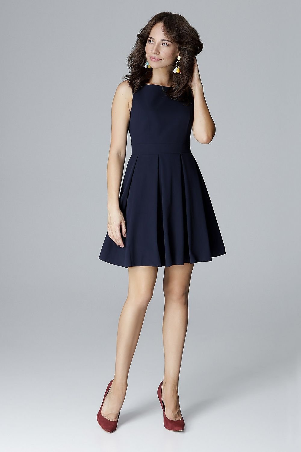 A sleeveless dress with a fitted top, low feminine neckline, and a waist-cut design with a flared bottom arranged in wide folds, perfectly emphasizing and slimming the waist.






