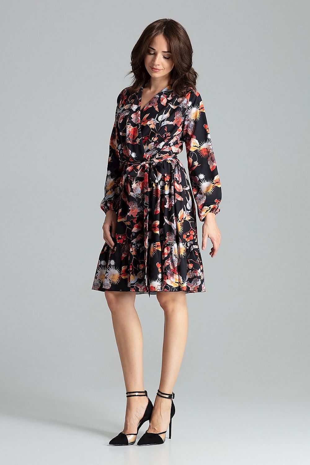 A floral midi dress featuring long sleeves with creased elastic cuffs, an envelope neckline, a frilled bottom skirt, an elastic waistband, and an additional sash to tie for a feminine silhouette.






