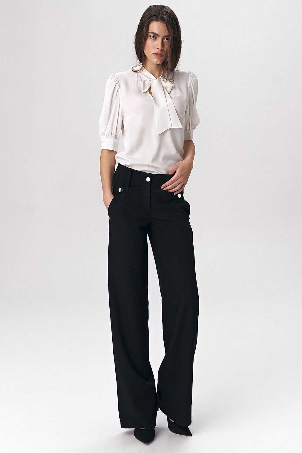 Black women’s trousers in a fashionable palazzo cut, featuring decorative press-studs that add a modern touch to classic office styling. Made from a comfortable viscose-blend fabric, these trousers offer both elegance and high wearing comfort, perfect for soft-office style.

