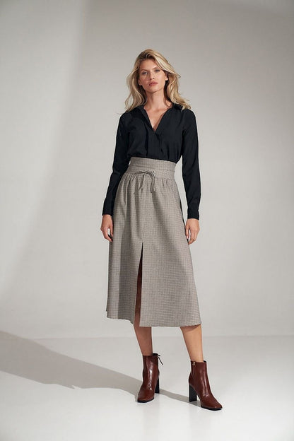 A long, flared pleated plaid skirt with a wide high waist, decorative binding, and a front slit. Fastened with a covered zip at the left side.

