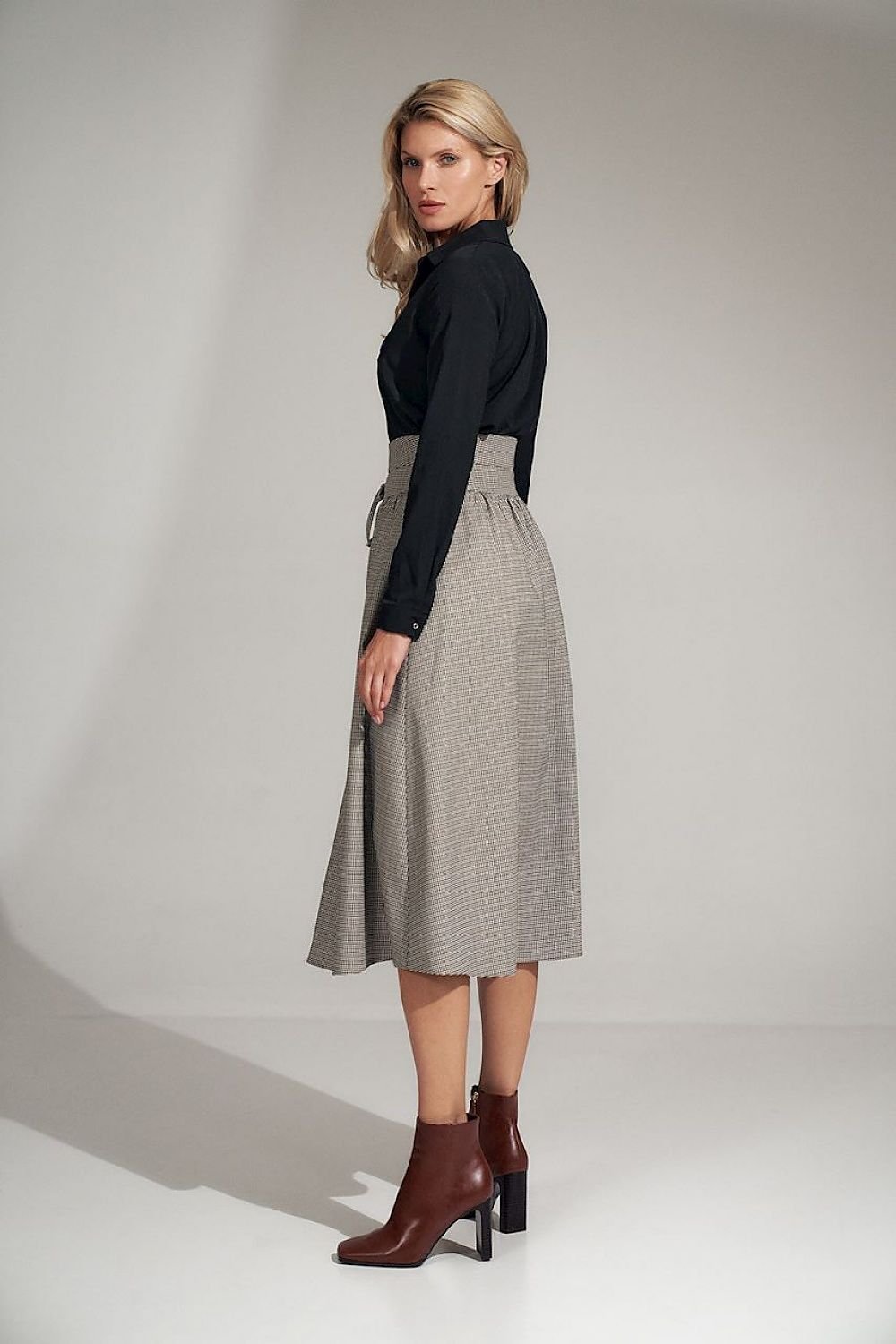 A long, flared pleated plaid skirt with a wide high waist, decorative binding, and a front slit. Fastened with a covered zip at the left side.

