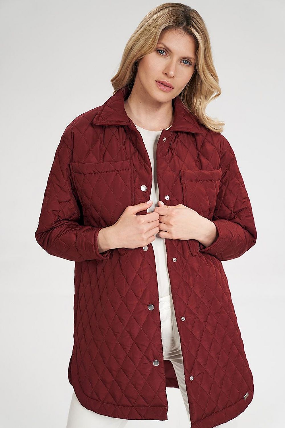 A stylish quilted extended jacket featuring semicircular side slits and press studs for a unique look. With side-seam pockets, large sewn-on bust-level pockets, and snap button cuffs on the sleeves, this jacket combines practicality and fashion. The lined interior adds comfort and warmth, making it perfect for cooler days.