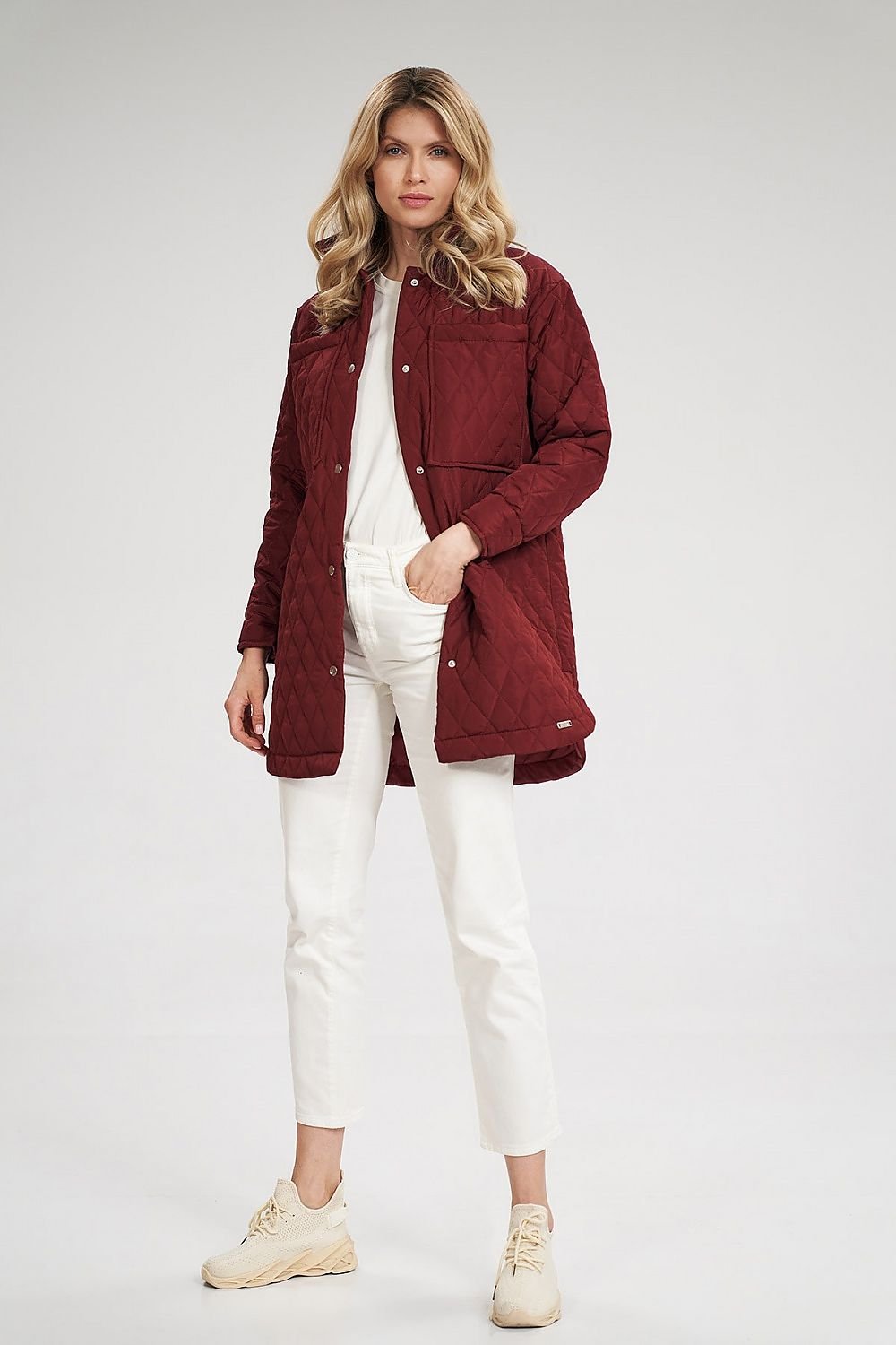 A stylish quilted extended jacket featuring semicircular side slits and press studs for a unique look. With side-seam pockets, large sewn-on bust-level pockets, and snap button cuffs on the sleeves, this jacket combines practicality and fashion. The lined interior adds comfort and warmth, making it perfect for cooler days.