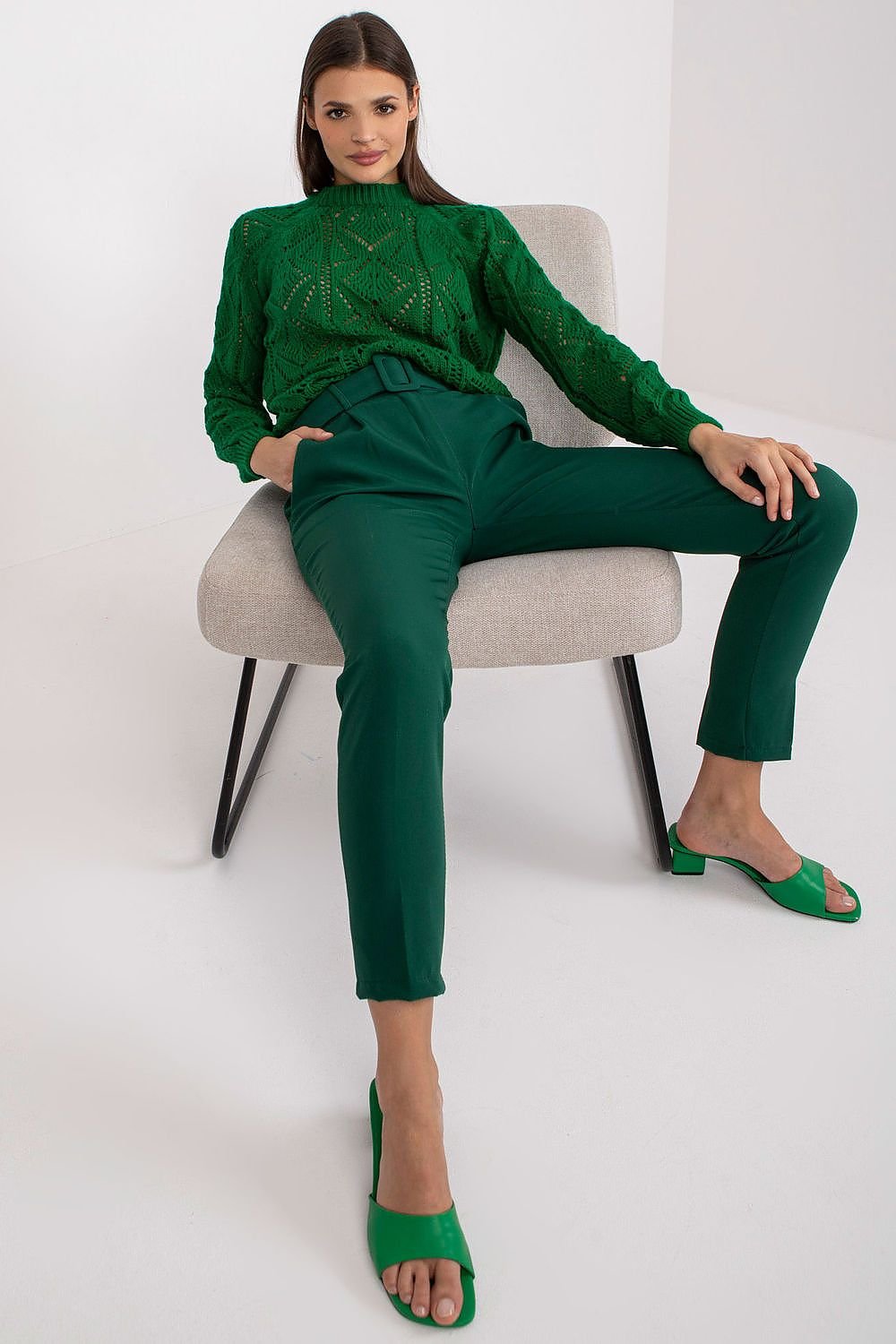 Women's green high-waisted pants featuring a zipper and button closure, slip-in side pockets, and a belt for a stylish and functional look.






