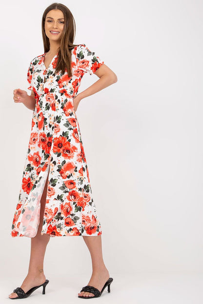 A breezy summer dress in vibrant floral fabric, featuring short sleeves, front buttons, a chic slit at the bottom, and a playful frill detail, perfect for warm sunny days.


