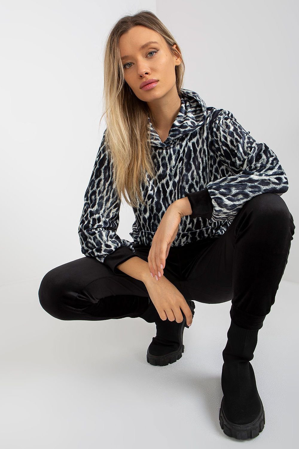 A comfortable velour set featuring a hooded sweatshirt with animal print and a kangaroo pocket, paired with long pants with slip pockets, offering a stylish and casual look.