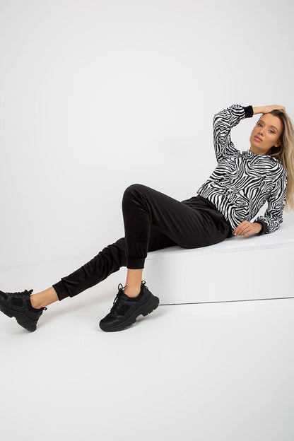 A comfortable velour set featuring a hooded sweatshirt with animal print and a kangaroo pocket, paired with long pants with slip pockets, offering a stylish and casual look.