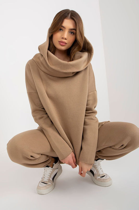 A women's set featuring an extended cut sweatshirt with long sleeves and a hood, paired with long pants that have a waist tie and pockets for added convenience.






