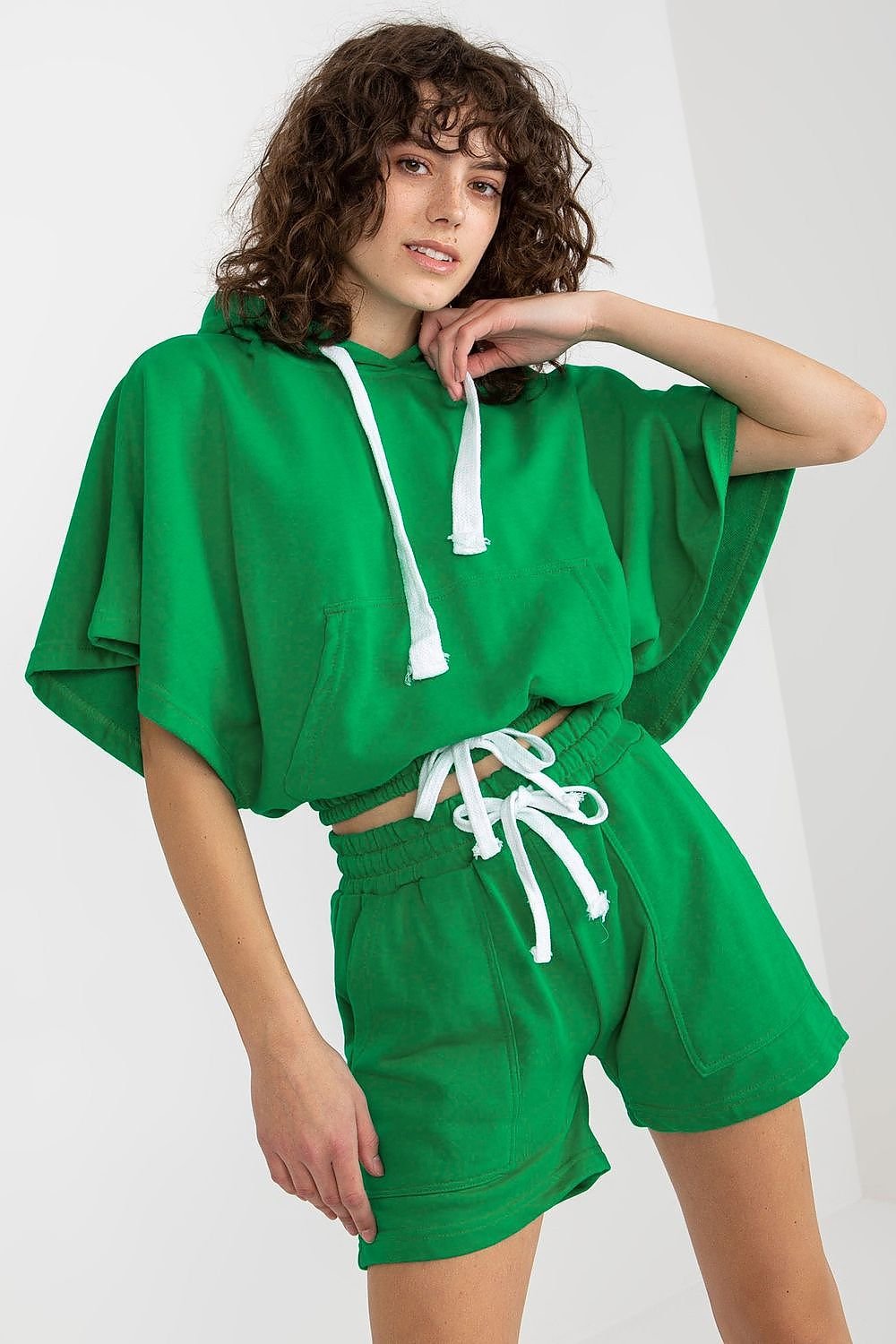 Comfortable GREEN tracksuit set featuring a hooded blouse with short wide sleeves and a kangaroo pocket, paired with shorts that have a waist tie and slip pockets. Ideal for casual wear.