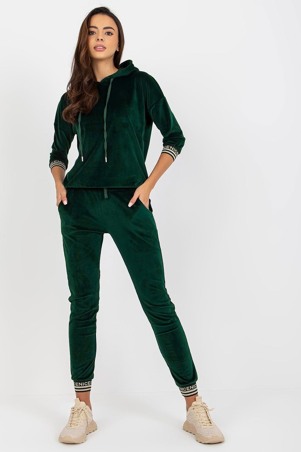 A stylish women's velour set featuring a hoodie with 3/4 sleeves, paired with long pants that have a waist tie and slip pockets. The set is finished with ribbed cuffs, adorned with a decorative print for added flair.


