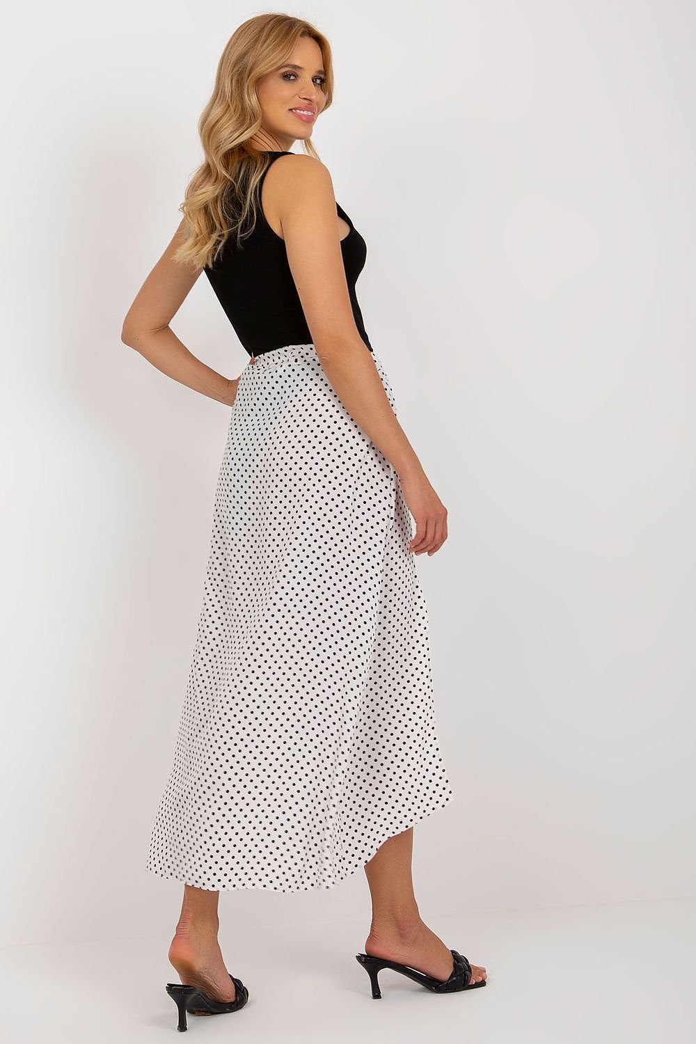 An asymmetrical skirt made of white fabric with navy blue polka dots, featuring two decorative slits on the front, creating a stylish and modern look.






