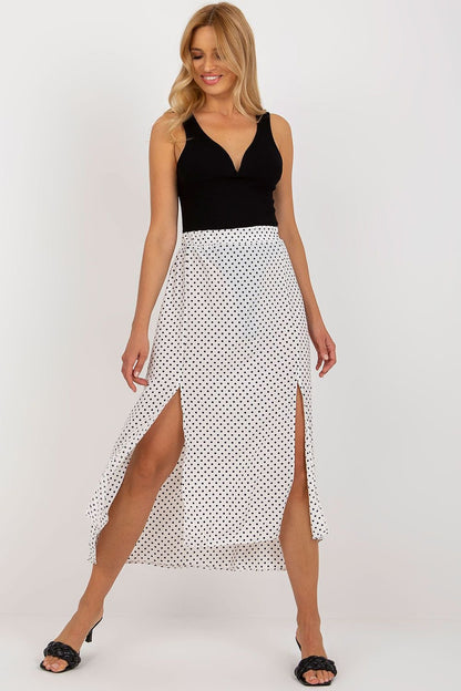 An asymmetrical skirt made of white fabric with navy blue polka dots, featuring two decorative slits on the front, creating a stylish and modern look.






