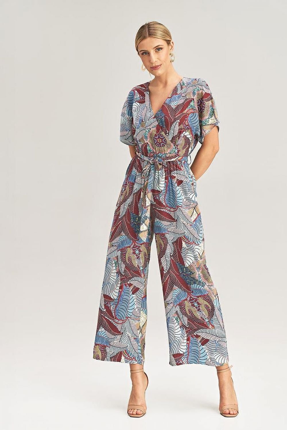 A woman wearing a stylish jumpsuit featuring a mix of floral, short sleeves, a V-neckline, and a tie belt at the waist.






