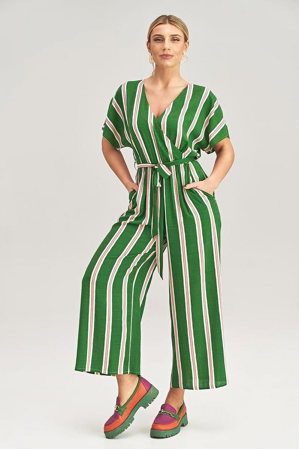 A woman wearing a stylish jumpsuit featuring a stripe pattern, short sleeves, a V-neckline, and a tie belt at the waist.






